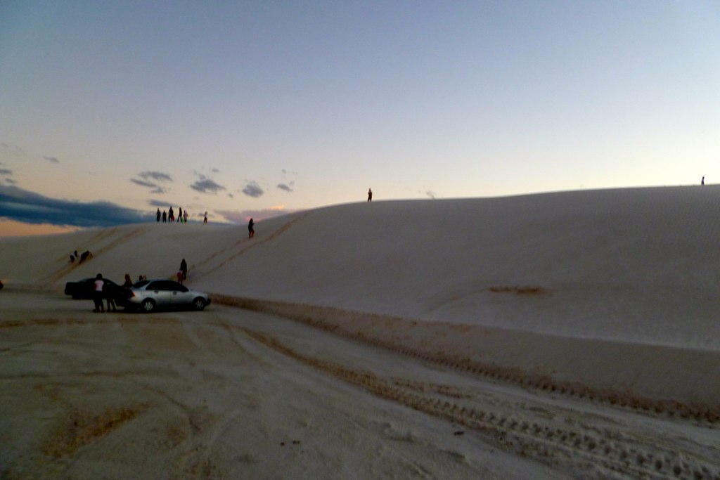 some people are standing on a sand dune