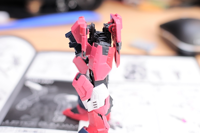 a robot with a pink, black and white head, standing on top of a table