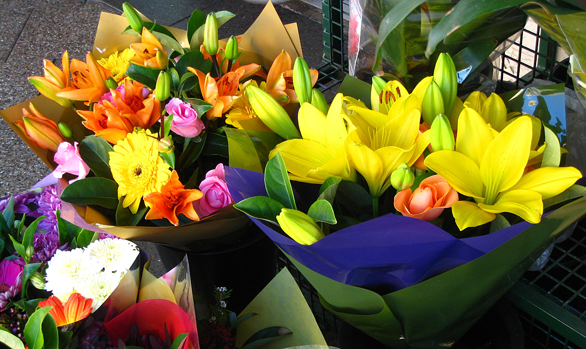 many bouquets of flowers on the ground outside