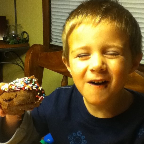 a boy holding up a large piece of cake with sprinkles