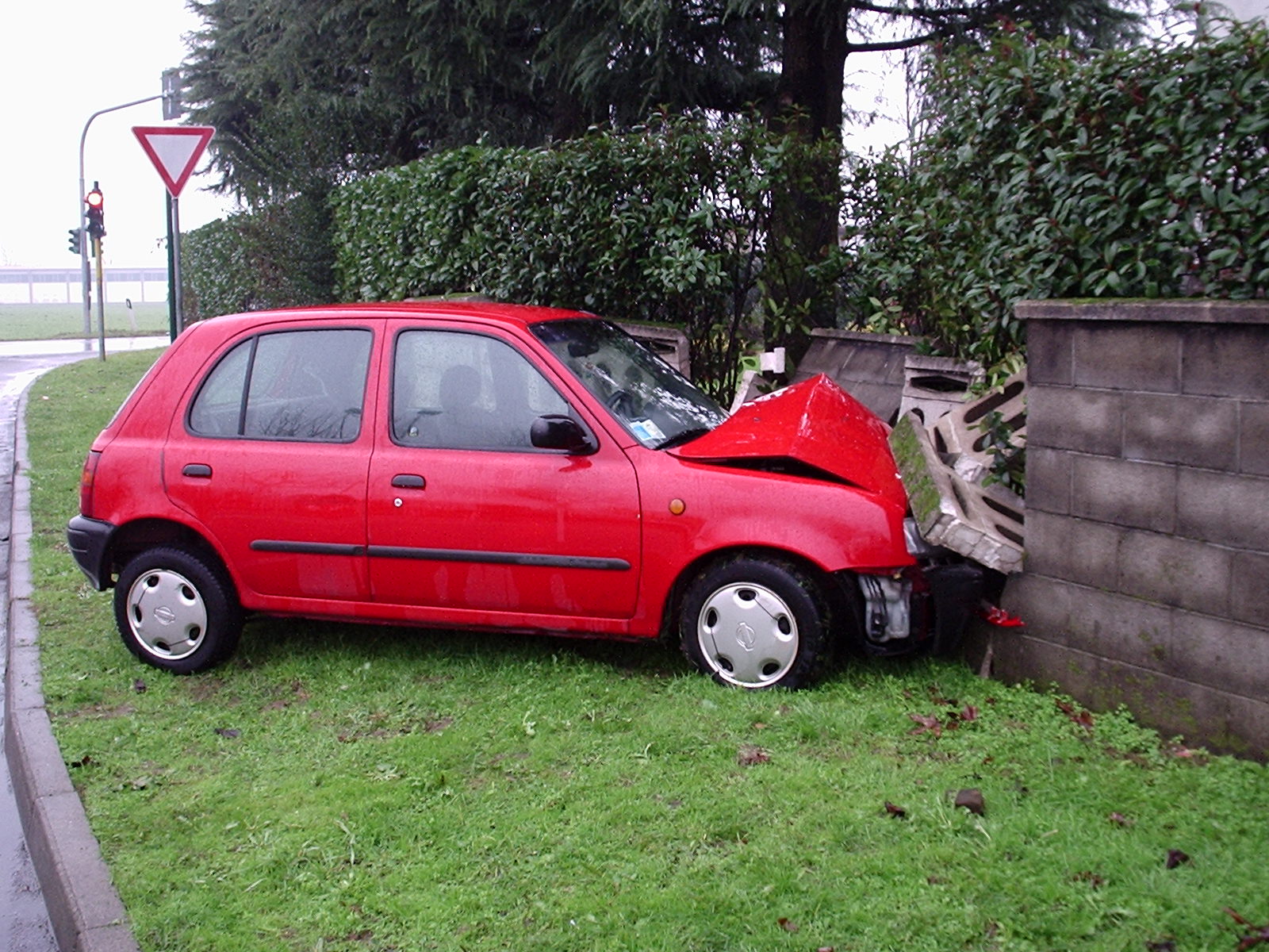 a red car is sitting on its side near a concrete block