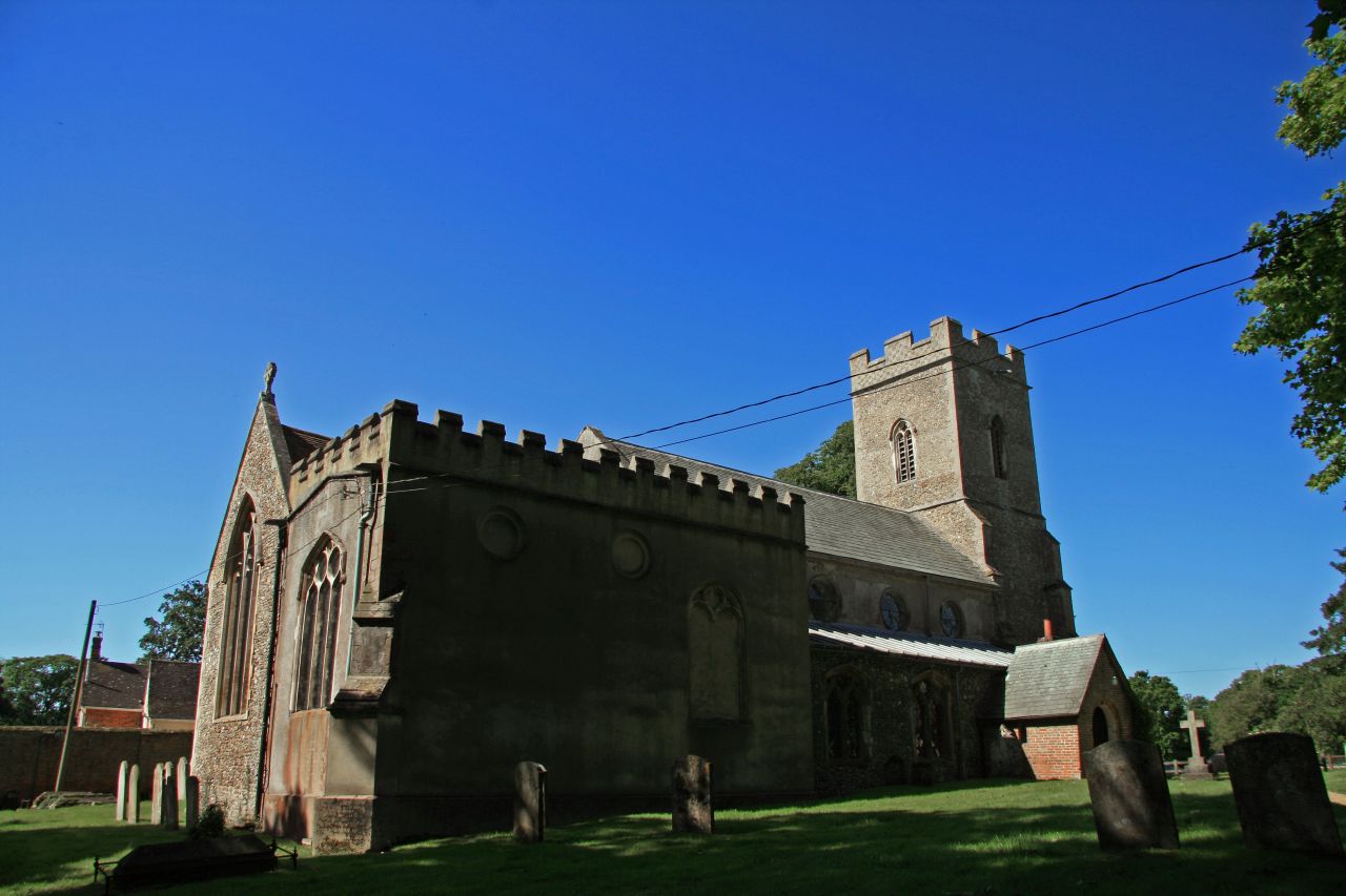 an old church with tall towers and a grave in the grass