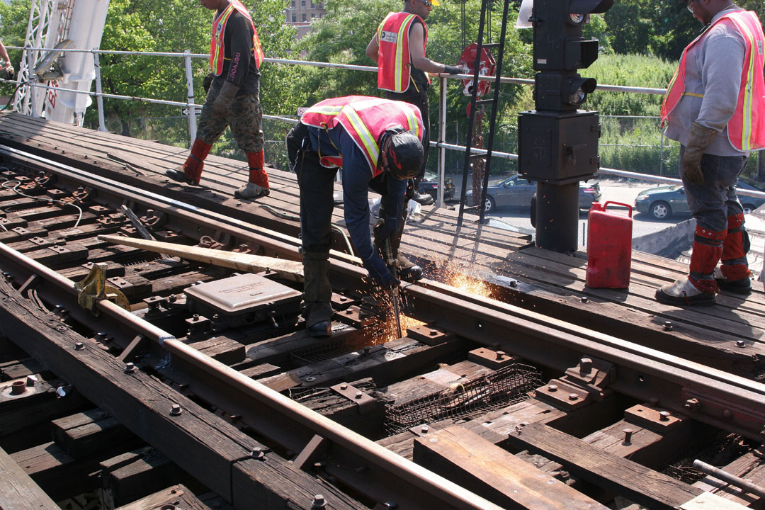 the people are wearing safety vests and grinding metal on a railroad track