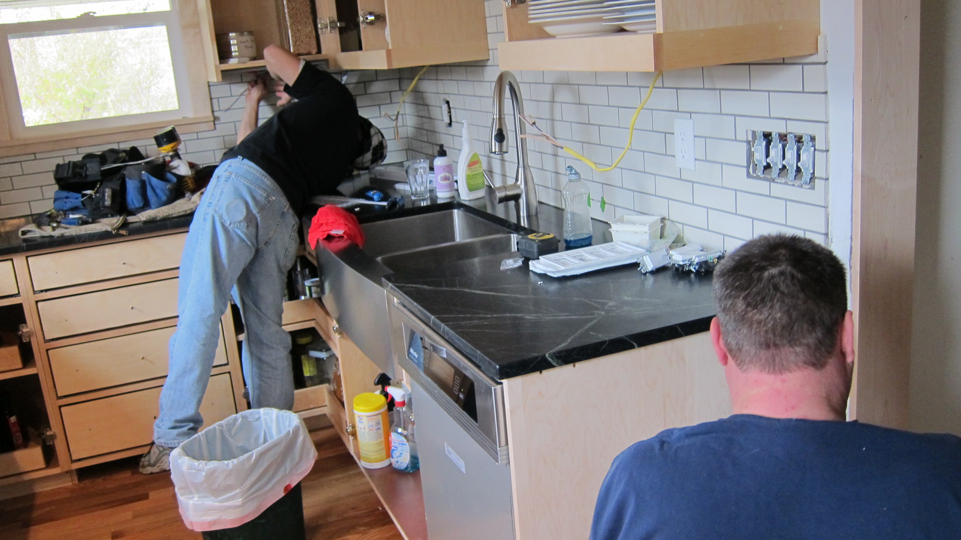 two men are doing work on a kitchen sink