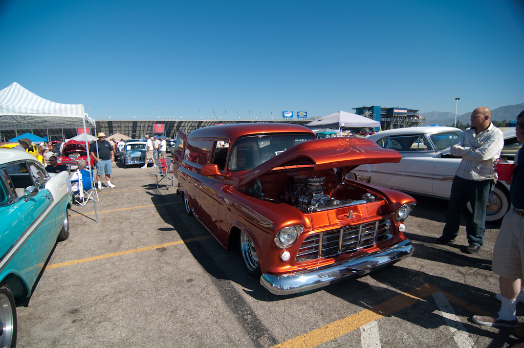 vintage cars parked in an open lot with people around them