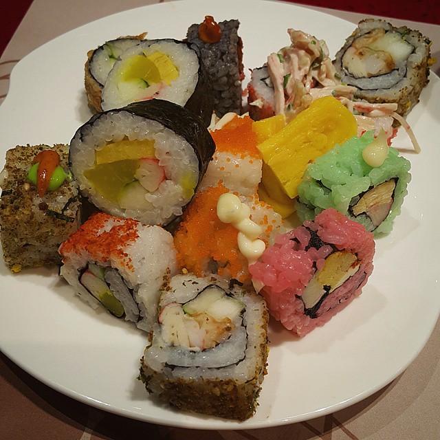 a plate topped with sushi covered in sauce and toppings