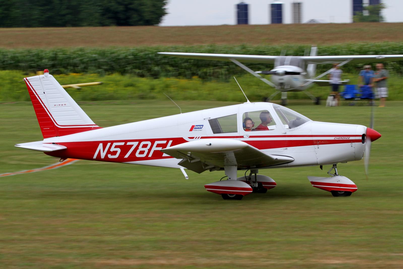 a small red and white plane is on a grass field