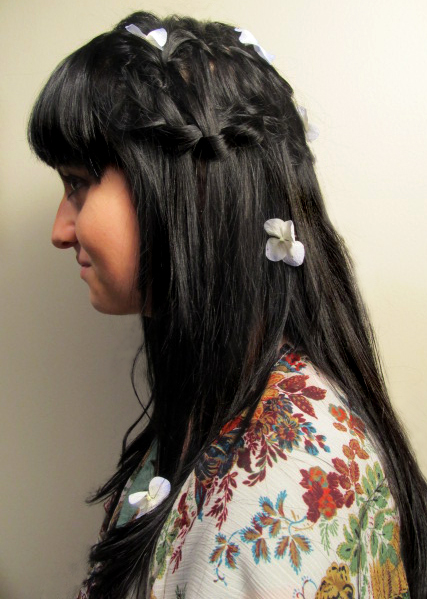 a lady with long dark hair is wearing four flowers in her hair