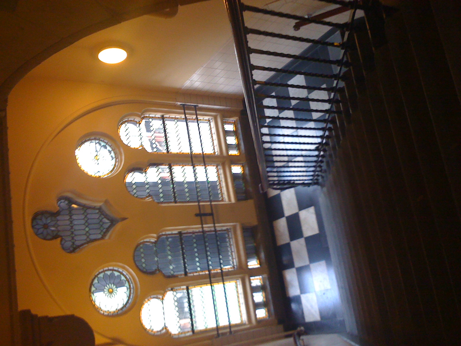 a view from the top level looking down at an ornate stairway with three windows