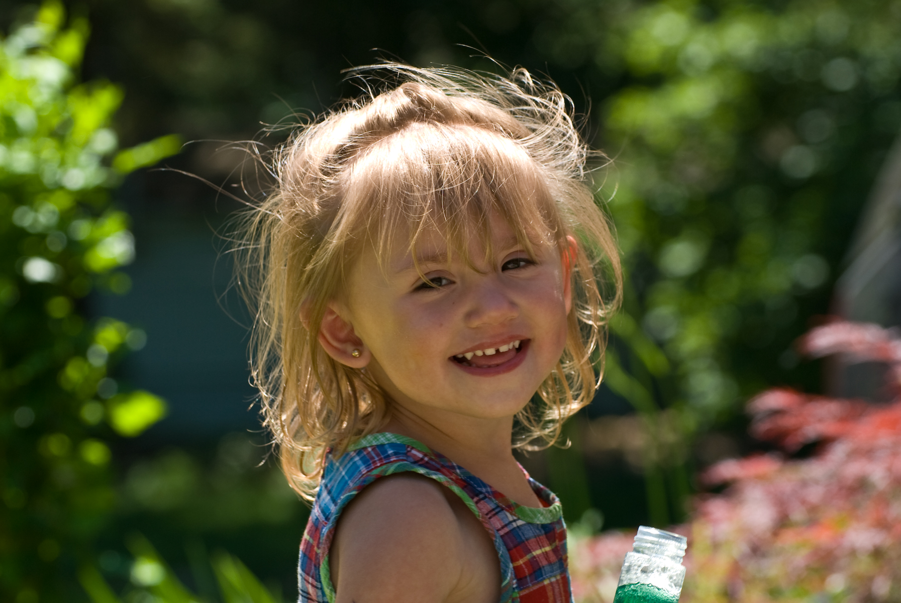 a little girl holding a green and white bottle and smiling