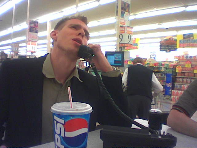a man sitting at a grocery store talks on a phone