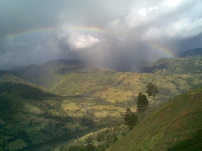 a rainbow shines over the mountainous landscape in the background