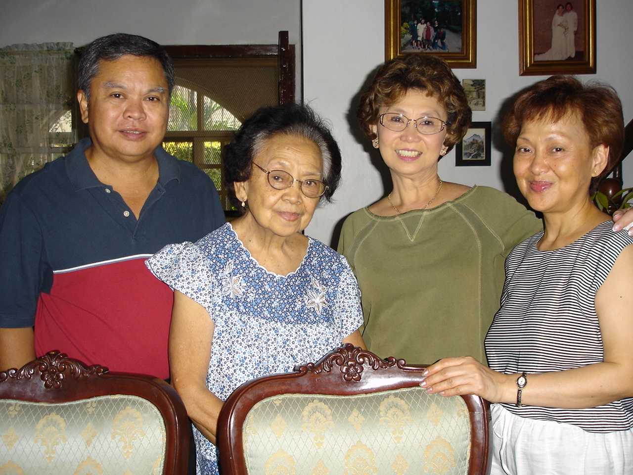 a man in glasses poses for a pograph with two older women and a young man