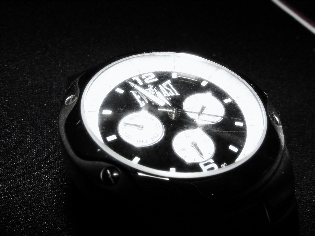 a watch with white dials is laying on a black surface