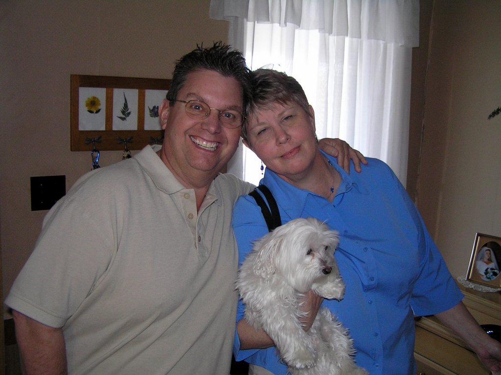 a woman standing next to a man holding a small white dog