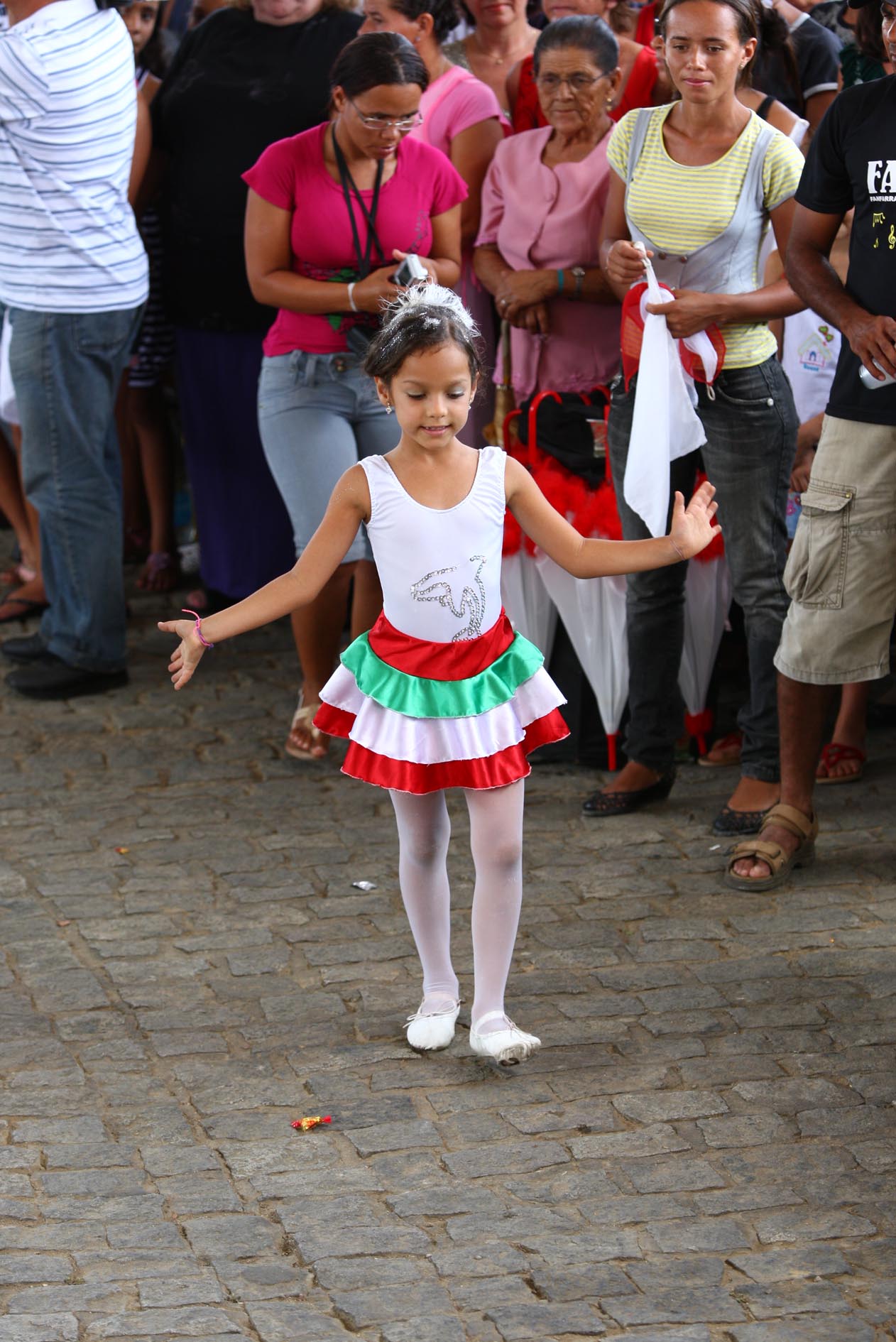 a little girl wearing a santa claus outfit is standing in front of a large crowd