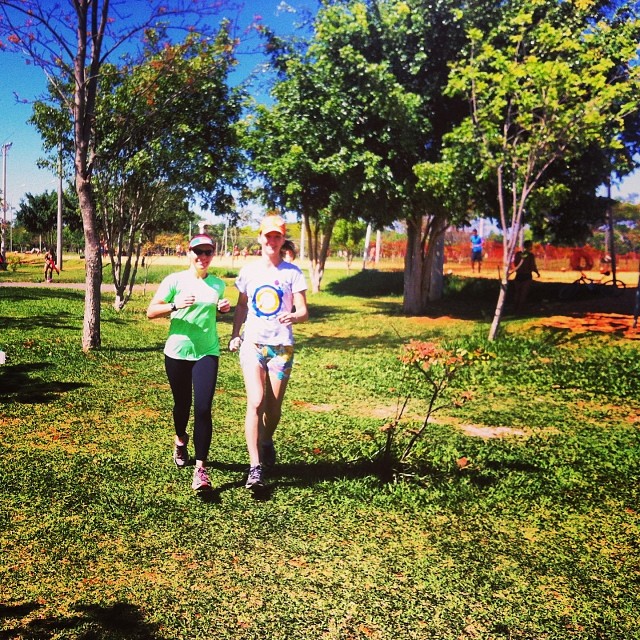 a couple running in a grassy park with trees