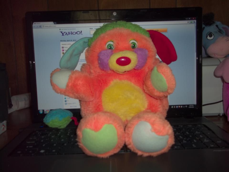 a teddy bear sits in front of an open laptop computer