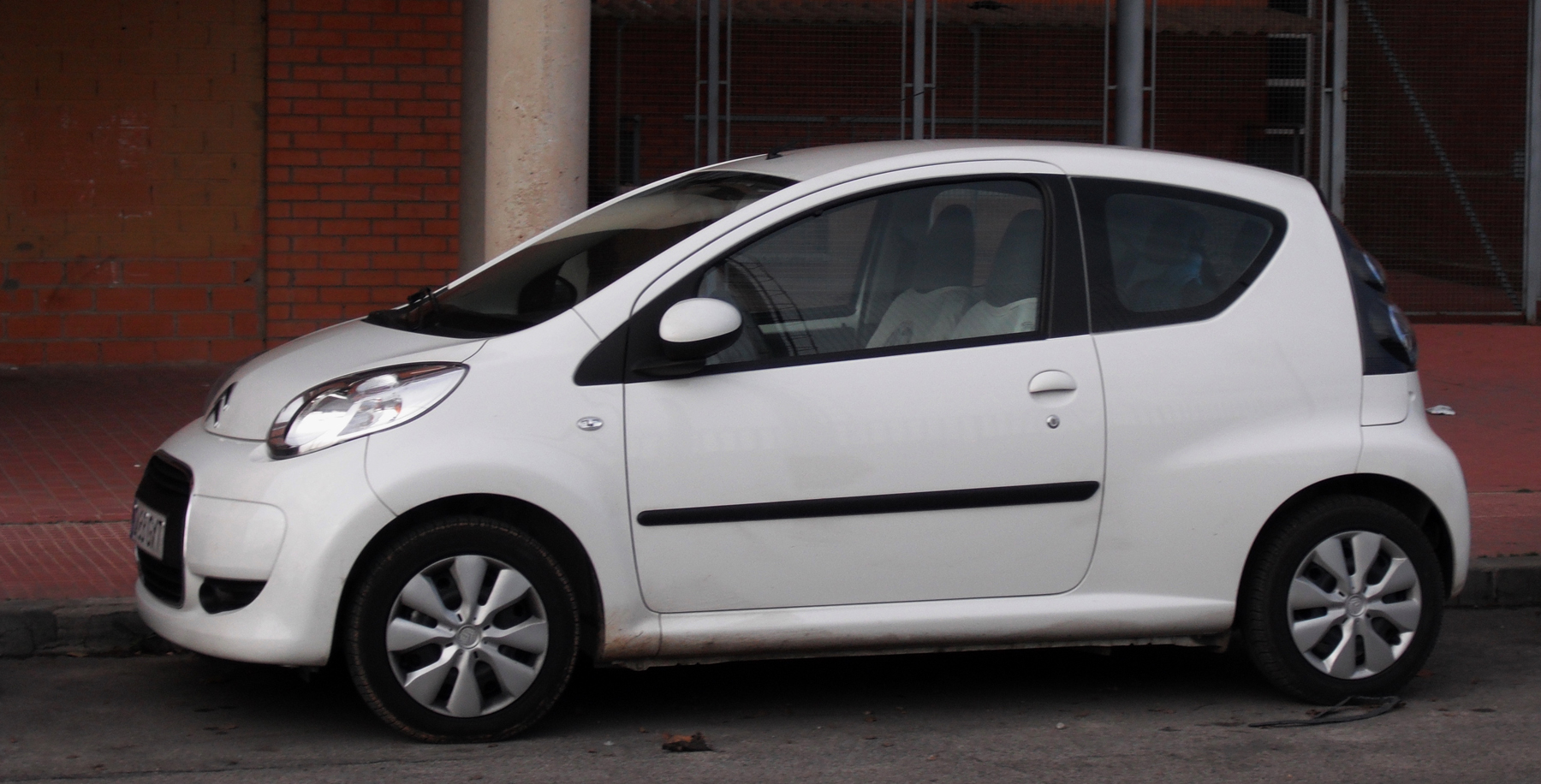 the small white car parked in front of a building