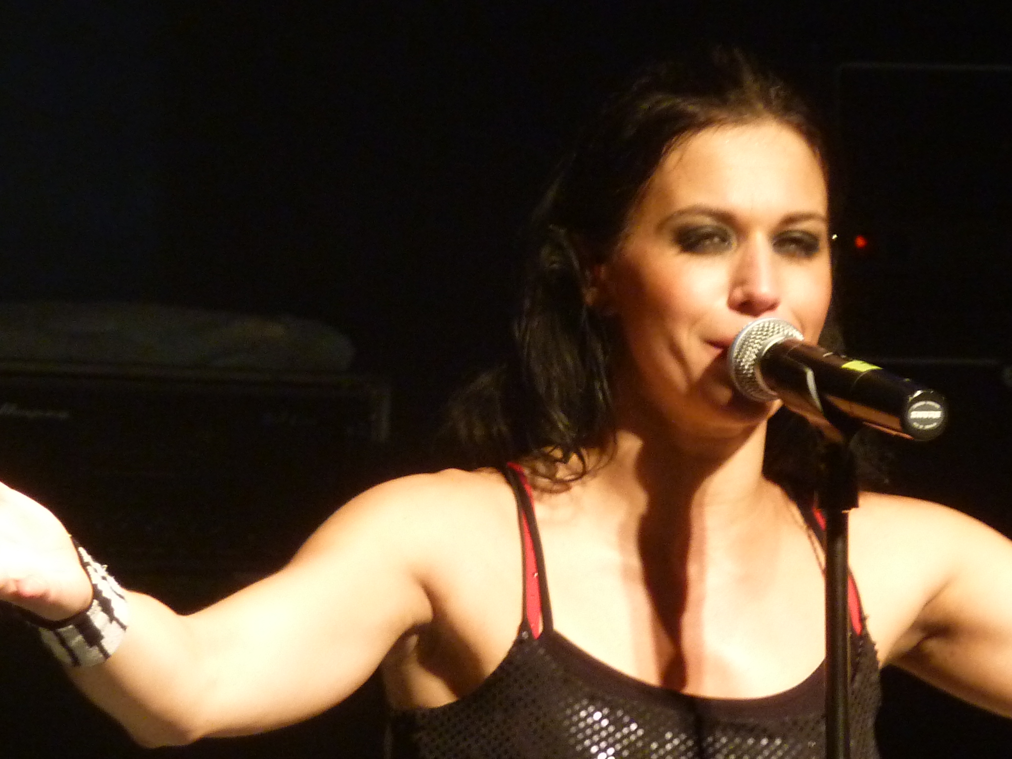 a woman with her arms extended and a microphone up in the air