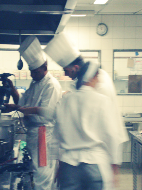 two chefs wearing white are preparing a meal