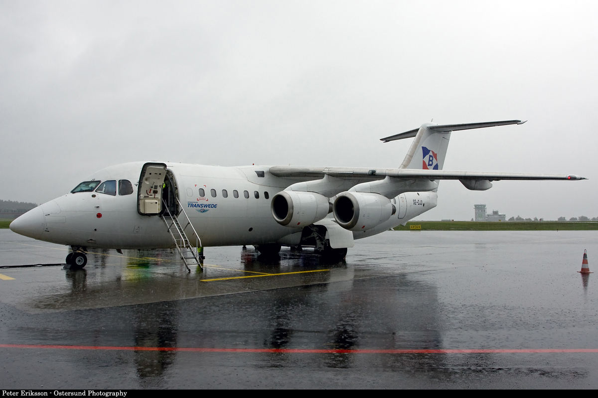 a propeller plane parked on the runway in a rain soaked area