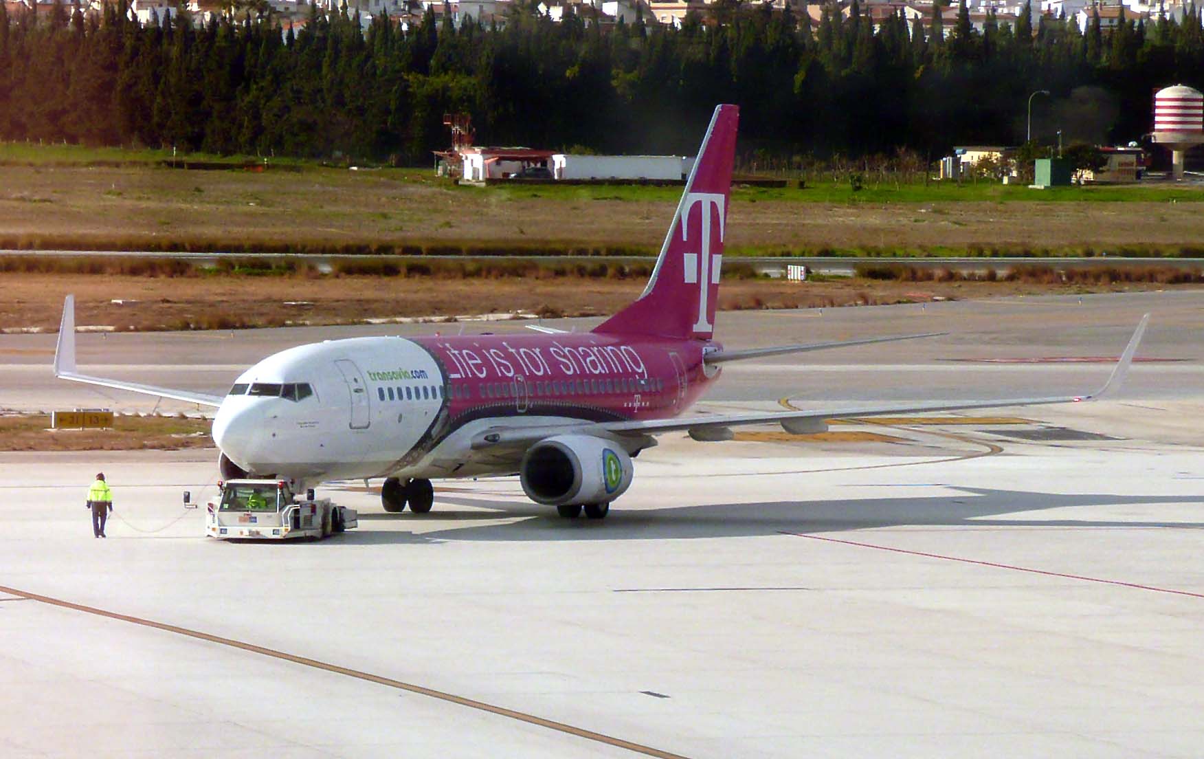 a pink and white jet parked on top of an airport tarmac