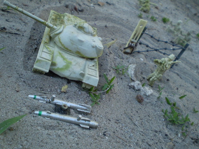 the shell of a tank, two pens, and several other debris in the sand