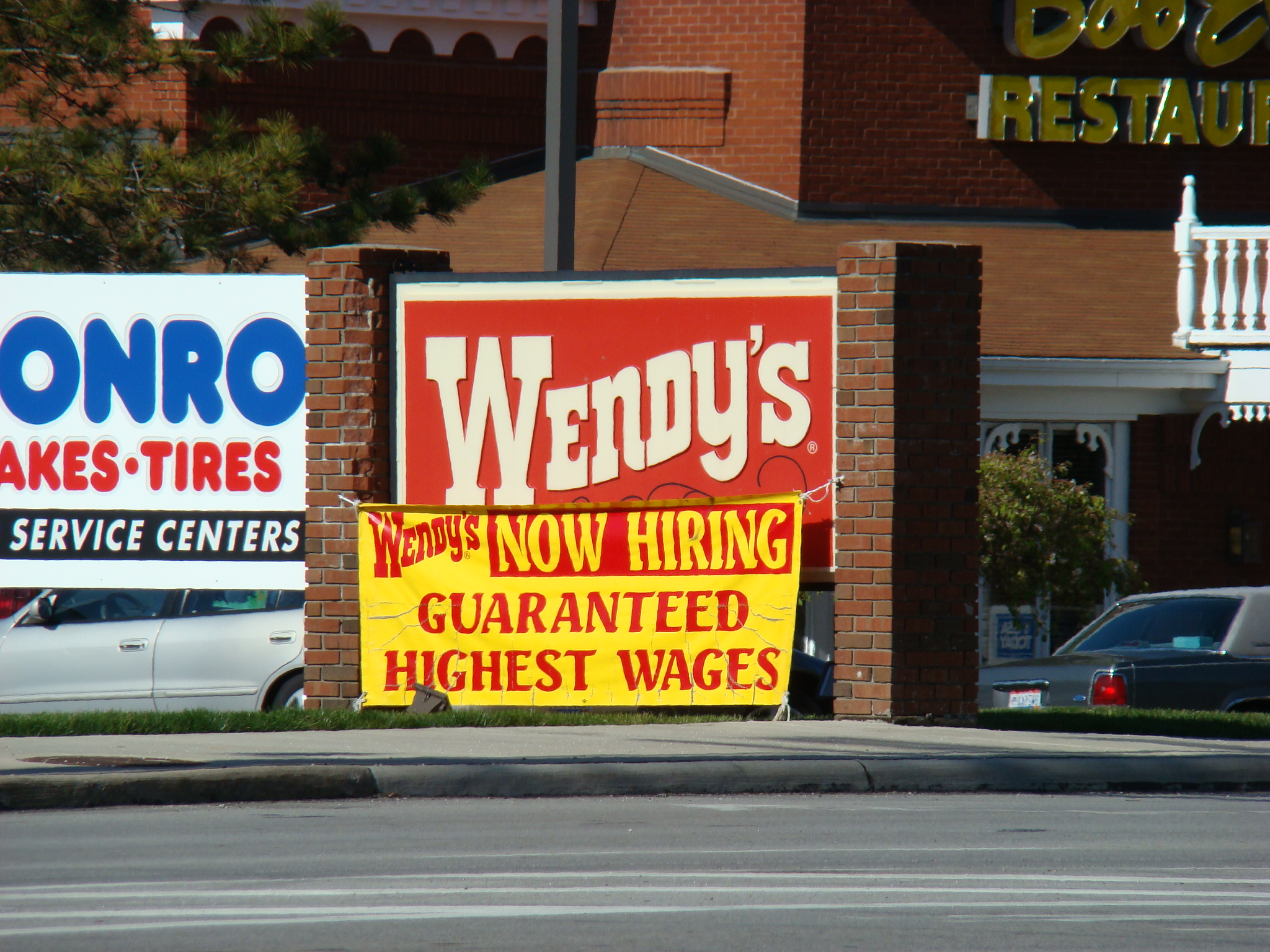 a yellow and red sign advertising wendy's, no hirings, and hight prices