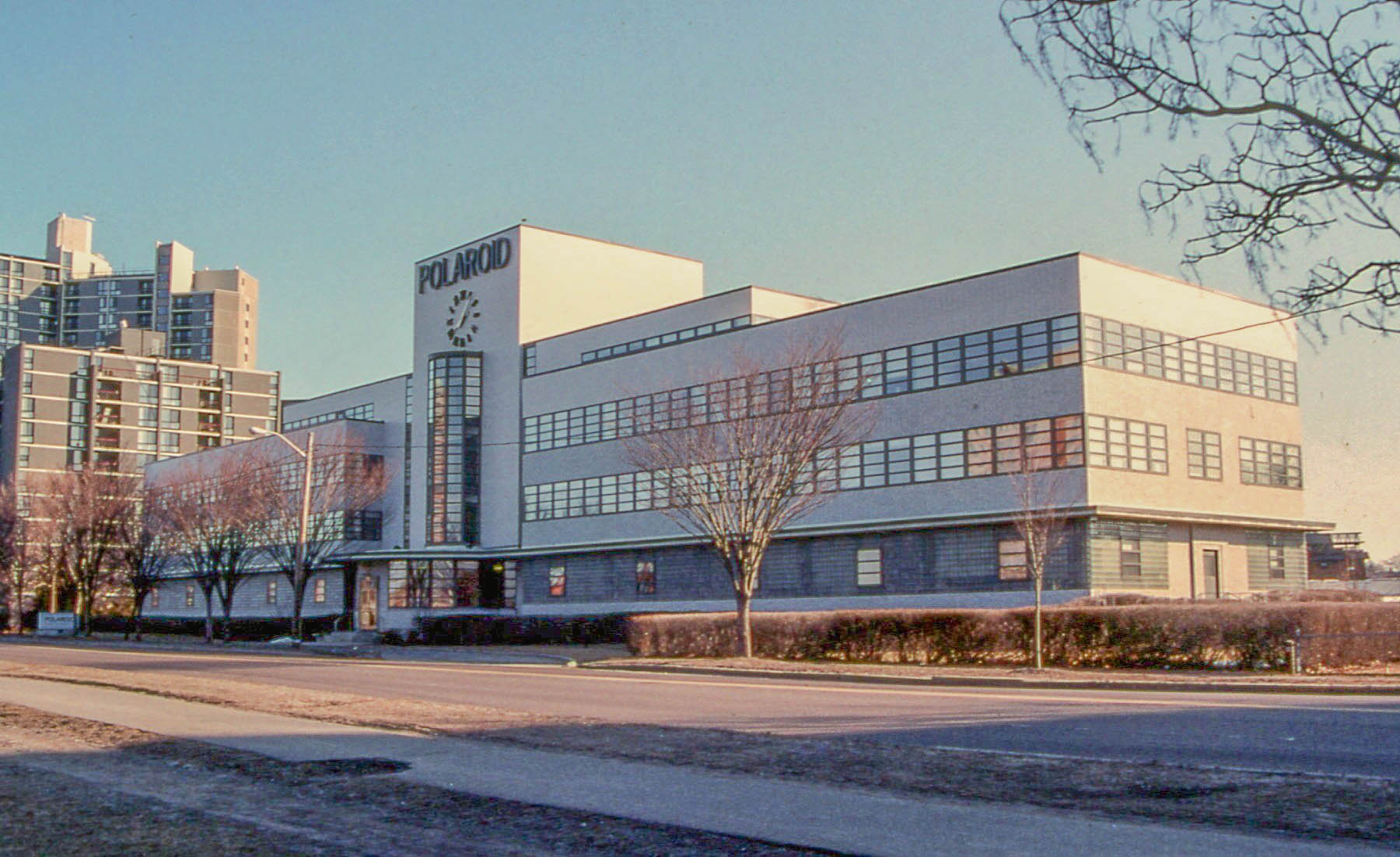 a building with several windows, a large flagpole and trees on a corner