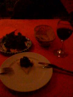a red dining table has a plate of food and two wine glasses