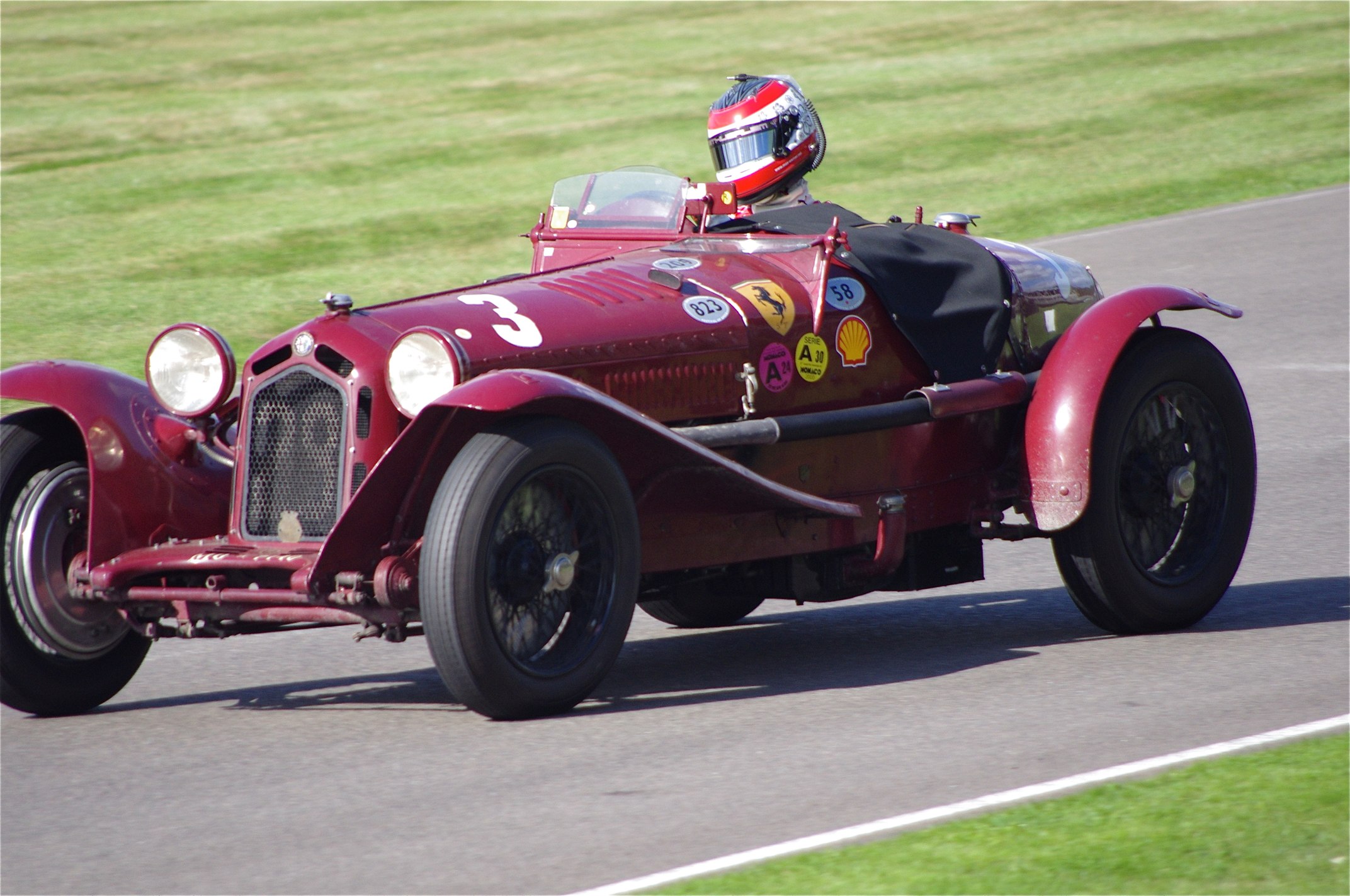 a vintage car driving down the road on a race track