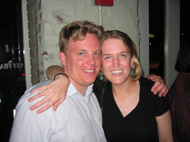 a woman emcing a man's shoulders at a bar