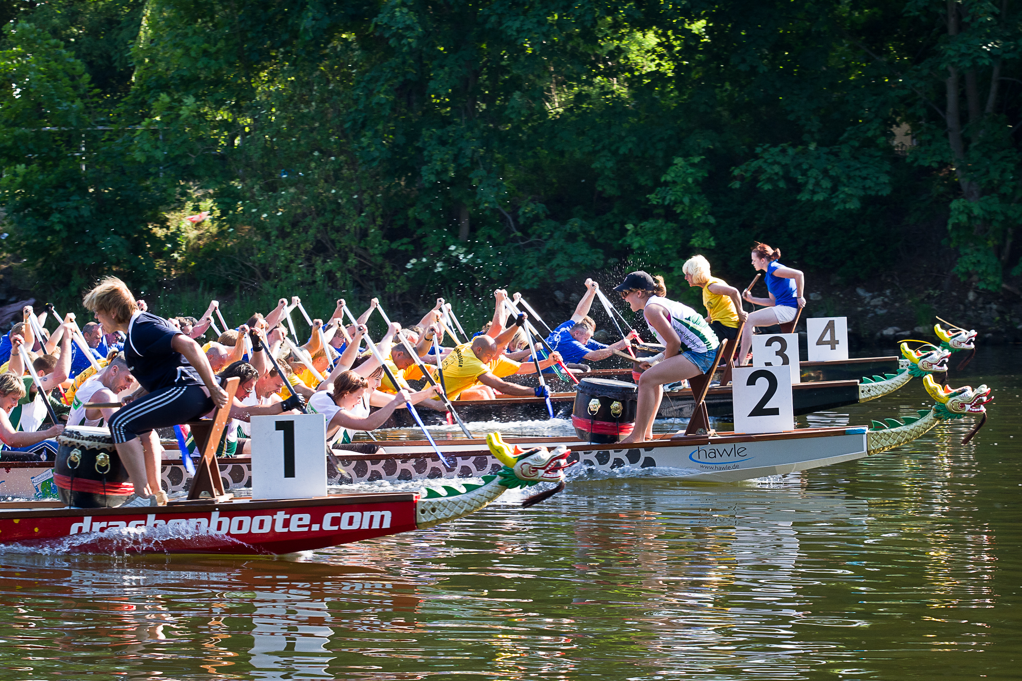 two teams of men race through the water in canoes