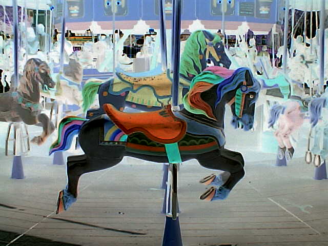 a carousel with multiple colored horses and a blue sky in the background