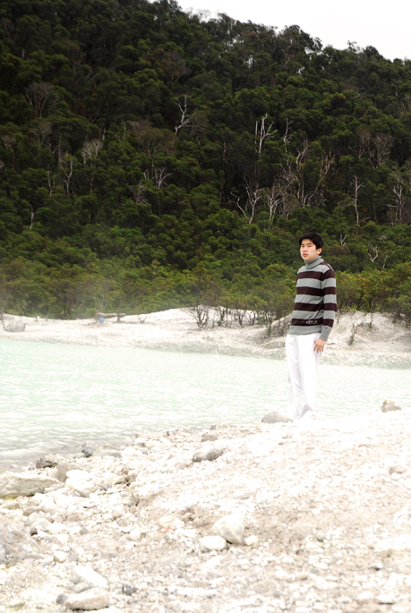 a man standing on a rocky beach next to the water