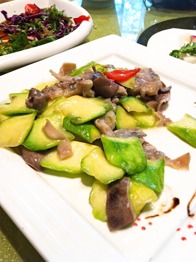 a plate with sliced up vegetables next to two plates with salad