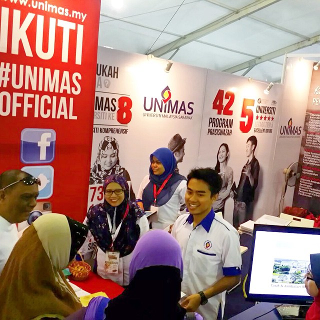 many people looking at laptops on a stand