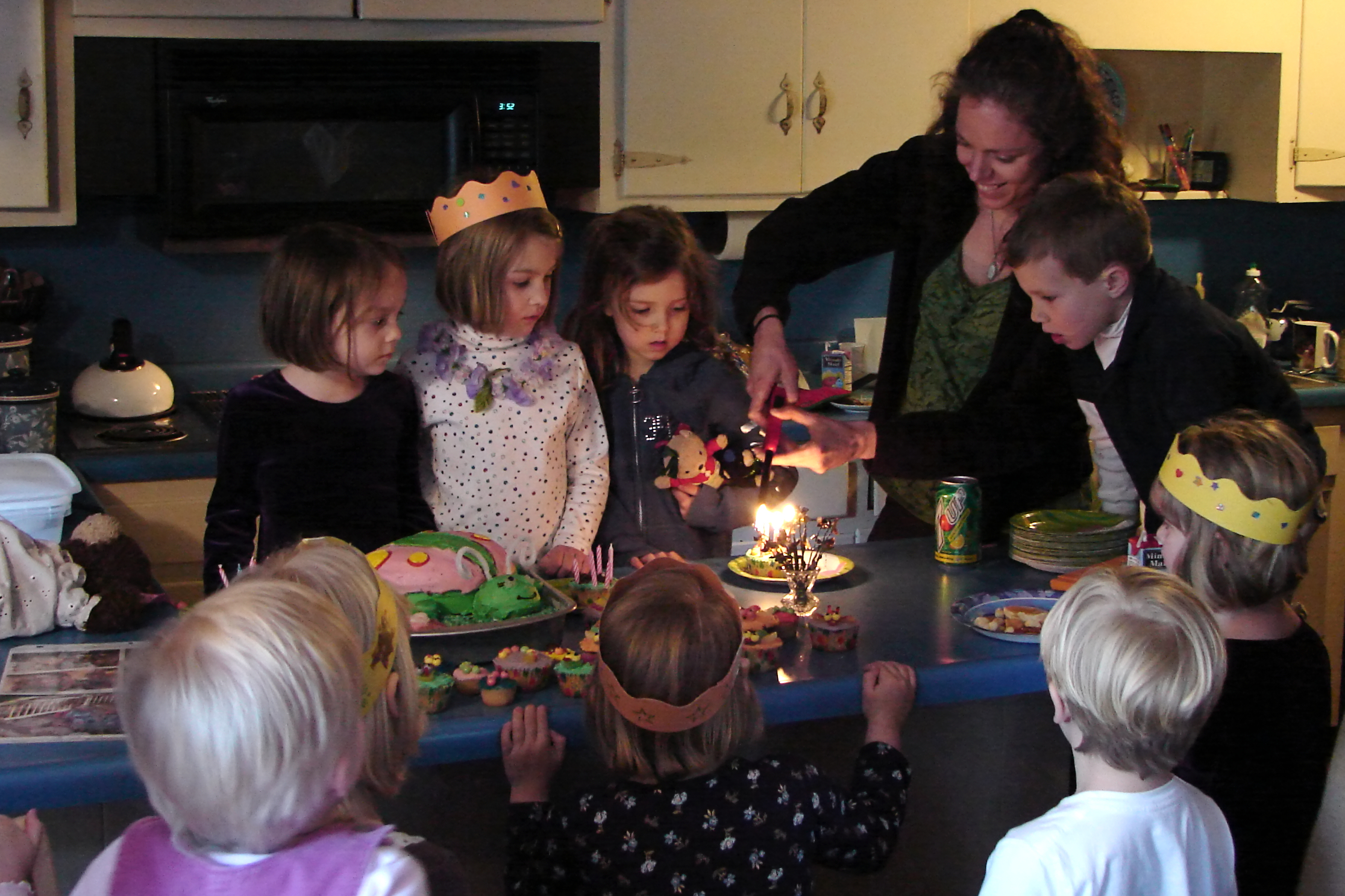 a mother lighting candles on her birthday cake with her children