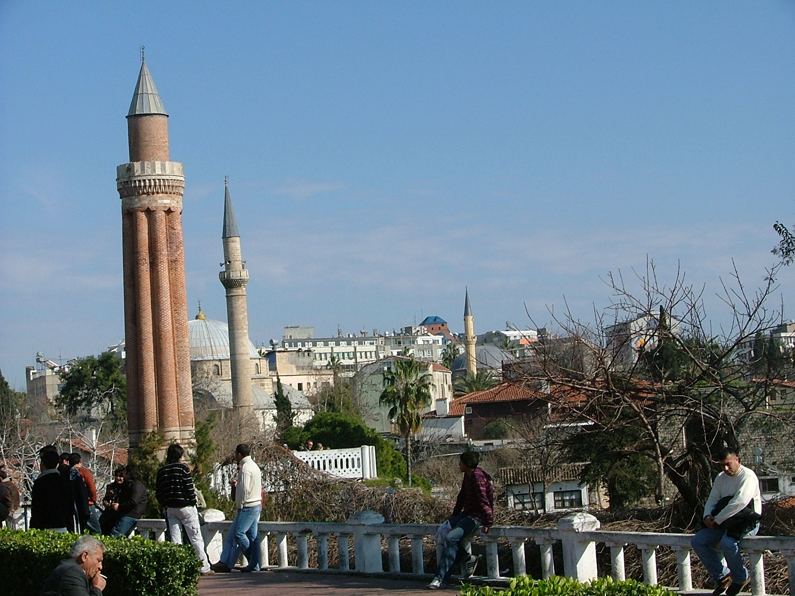 a group of people walk near a tower that has a clock on it