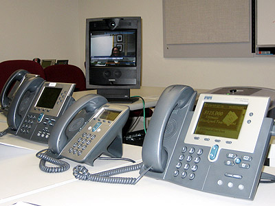 several telephone phones sit on an office desk with the screens open