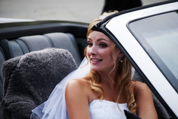 a beautiful blonde bride sitting in a black car