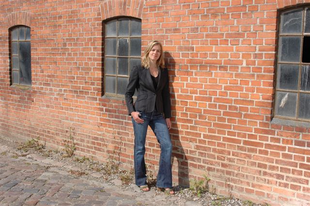 a woman leaning against a brick wall on the side of a building