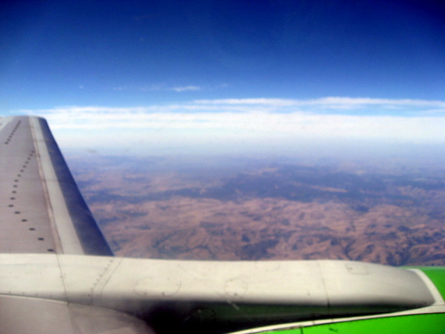 the wing of an airplane flying over a mountain range