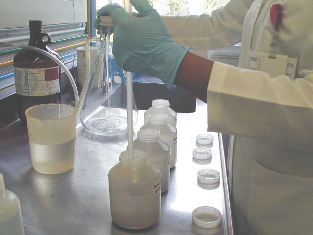lab coats holding up beakle containers, flasks and vials