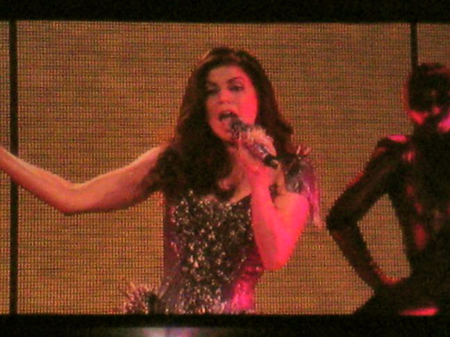 a woman in a silver and black dress holding a microphone