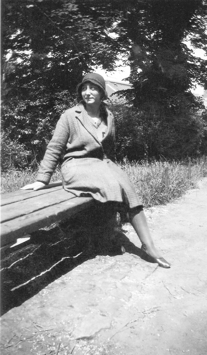 an old black and white po of a woman sitting on a park bench