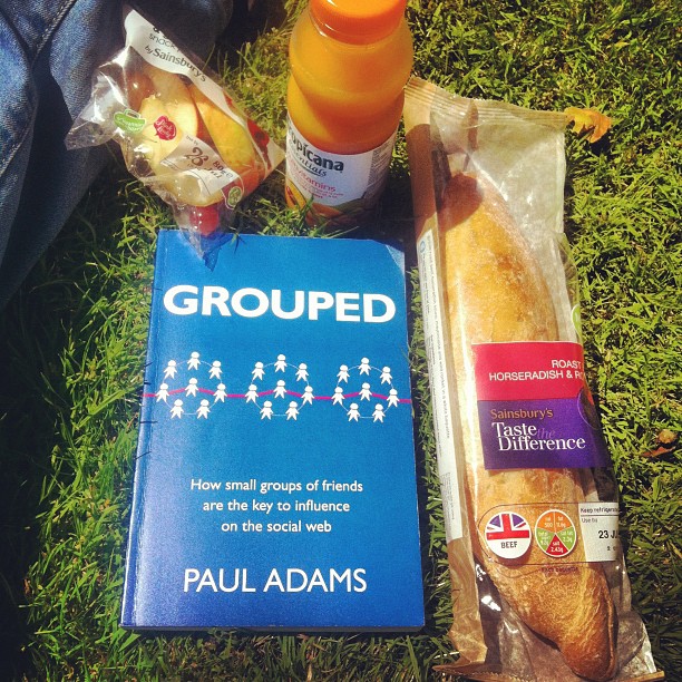 a book, bread and other food sitting in the grass