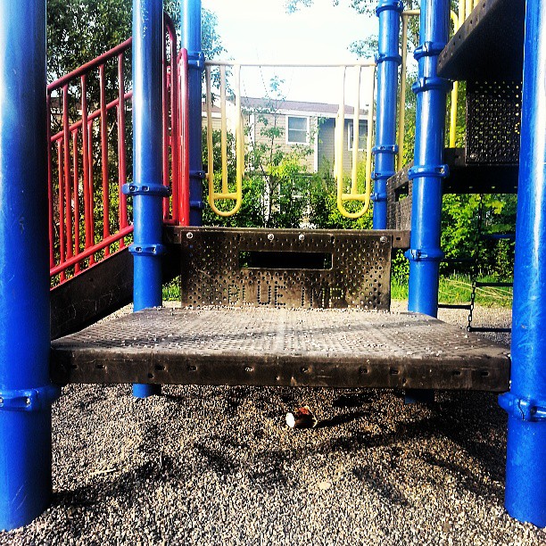 a dirty playground with a blue railing and swings