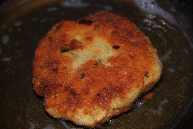 two fried fish patties being cooked in a pan